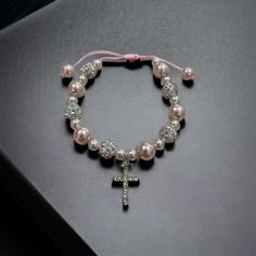 Celebrate a special moment of faith with our handcrafted Beaded Confirmation Bracelet. This elegant piece features a delicate crystal cross, surrounded by beautiful pink and white beads, symbolizing purity and love. Product Details Design: Hand-beaded with pink and white beads, accented by a sparkling crystal cross. Adjustable Fit: Equipped with an adjustable sliding knot, ensuring a perfect fit for any wrist size. Material: High-quality glass beads and a shimmering crystal cross centerpiece. Ve Beaded Cross Jewelry For First Communion, Cross-shaped Beaded Jewelry For First Communion, Adjustable Pink Cross-shaped Jewelry, Adjustable Rosary Bracelet With Round Beads For Baptism, Adjustable 8mm Beads Rosary Bracelet For Baptism, Adjustable Cross Bracelet For First Communion, Adjustable Cross Bracelets For First Communion, Adjustable Spiritual Rosary Bracelet For Mother's Day, Adjustable Rosary Bracelet With Round Beads For First Communion