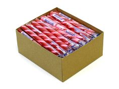 a box filled with pink candy sticks on top of a white table next to a cup