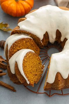 a pumpkin bundt cake with white icing on a wire rack