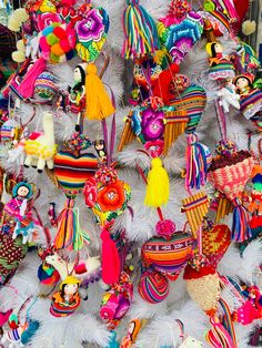 many colorful ornaments are hanging on a white tree