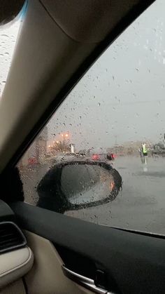 rain is falling on the windshield of a car as it drives down an airport runway