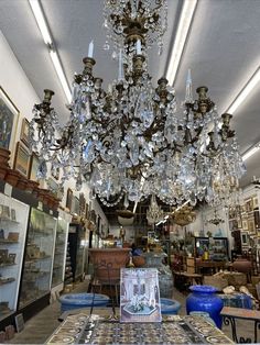 a chandelier hanging from the ceiling in a room filled with furniture and antiques