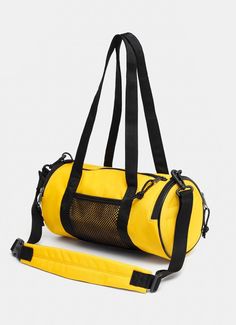 a yellow duffel bag sitting on top of a white floor next to a black strap