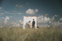 two people standing in front of a white box with clouds behind them on a sunny day