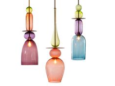 three multicolored glass pendants hanging from a ceiling fixture with lights on them