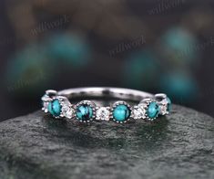 a turquoise and white diamond ring sitting on top of a rock