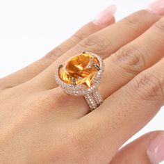 This exquisite ring features a stunning Citrine as the center stone, radiating vibrant hues of golden yellow. The Citrine is complemented by an array of White Zircon accent stones, adding a touch of brilliance and sparkle to the piece. The design showcases a luxurious rose gold-plated band, enhancing the warm tones of the Citrine. The intricate setting highlights the gemstone's natural beauty, making it a perfect statement piece for any occasion. This piece is inspired by the Art Deco era, known Orange Diamond Ring Fine Jewelry For Gift, Fine Jewelry Orange Diamond Ring As Gift, Fine Jewelry Orange Diamond Ring For Gift, Orange Diamond Ring For Gift, Fine Jewelry, Orange Diamond Ring As A Gift, Orange Topaz Rings For Anniversary, Orange Diamond Ring For Gift, Elegant Topaz Rings With Stones, Elegant Orange Diamond Ring For Gift