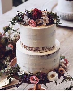 there is a three layer cake with flowers on the top and bottom, sitting on a wooden table