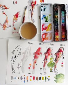 some watercolors are sitting on a table next to a cup and paintbrushes