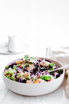 a white bowl filled with salad next to a cup