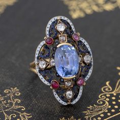 Only one of the prettiest and most special ring we have had the pleasure of owning! The Victorian revival gallery appears to have started its life as a brooch with a shank subsequently added. Really charming details with white enamel and different color gemstones. The sapphire is a stunning medium, almost cornflower blue color - a special no-heat gem! On the finger, it is pretty special. Most def a one of a kind piece. 18kt & 14kt yellow gold Size 6.5 & resizable 4.13ct Sapphire Measures: 10.58 Fine Jewelry Diamond Gemstone Brooches, Luxury Enamel Gemstone Ring For Gift, Elegant Multi-stone Oval Brooch, Elegant Multi-stone Oval Brooches, Elegant Blue Enamel Ring With Gemstone, Elegant Oval Multi-stone Brooches, Formal Enamel Ring With Gemstone, Luxury Sapphire Brooch Jewelry, Exquisite White Gold Gemstone Brooches