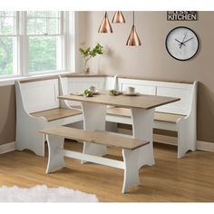 a kitchen table with benches and a clock on the wall above it, in front of a window