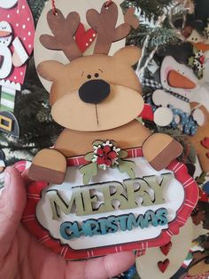 a hand holding up a christmas ornament with a reindeer on it's head