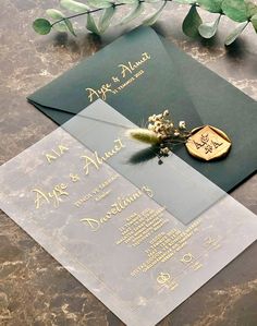 an elegant wedding card with gold foil on it and a flower in the middle is sitting on a marble table