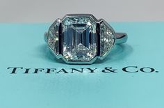 an emerald cut diamond ring on top of a tiffany & co box