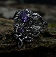 Handcrafted for enchanting souls, our ethereal fairy witchy wedding ring set embodies mystical allure and magical elegance. Crafted from sterling silver, it features intricate details inspired by celtic fantasy, including delicate branches and leaves, complemented by a striking dragon motif. The enchanting purple hue adds a touch of magic to this silver witches knot jewelry, making it a perfect choice for those seeking a unique and mystical accessory set for their special day. Characteristics: Metal - Recycled solid sterling silver  Stone - Cubic Zirconia Finish - Oxidized. View all silver dragon rings: https://www.etsy.com/shop/TinyShinyJewel?ref=seller-platform-mcnav&section_id=45210616 Care instructions: To care for the ring, avoid contact with water and chemicals such as perfumes and l Sterling Silver Fantasy Ring, Gothic Gemstone Wedding Ring, Gothic Wedding Gemstone Ring, Sterling Silver Magical Promise Ring, Gothic Wedding Ring With Gemstone, Silver Fantasy Promise Ring, Fantasy Sterling Silver Ring, Dragon Wedding Ring, Nature-inspired Silver Amethyst Jewelry