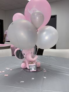 an elephant holding balloons on top of a table