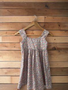 This cute little dress is a classic design that will look adorable on any little girl. Pull over style with lots of brightly coloured flowers made in Liberty Tawny lawn.  100% Cotton Age.      Chest      Waist.     Hips  1.              20.          19.5.           -  2.              21.          20.              -  3.              22.         20.5.           -  4.              23.         21.             24  5.              24.         21.5.          25  6.              25.         22. Cute Sundress With Ditsy Floral Print For Garden Party, Cute Ditsy Floral Print Sundress For Garden Party, Cute Ditsy Floral Sundress For Garden Party, Playful Cotton Floral Print Sundress, Playful Multicolor Cotton Floral Dress, Multicolor Cotton Floral Dress With Ruffles, Multicolor Cotton Floral Dress With Short Sleeves, Cute Multicolor Sundress For Garden Party, Playful Floral Print Cotton Dress