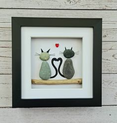 two cats sitting next to each other on top of a wooden branch in a frame