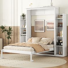 a white bed sitting on top of a wooden floor next to a book shelf filled with books