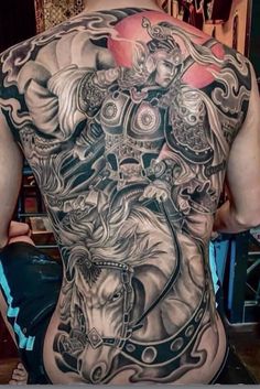 the back of a man with tattoos on his body and an image of a woman riding a horse