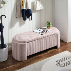 a pink bench with an umbrella on it in a white room next to a rug