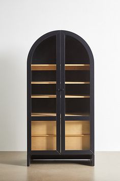 an arched display case with glass doors on the front and bottom, in dark wood