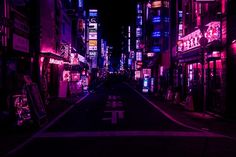 an empty city street at night with neon signs