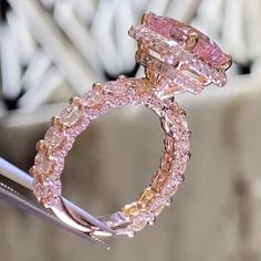 a pink diamond ring sitting on top of a piece of metal