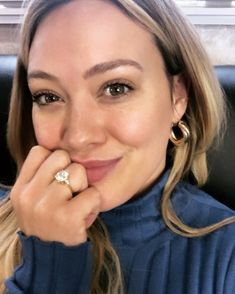 a woman sitting in a chair with her hand on her chin and smiling at the camera