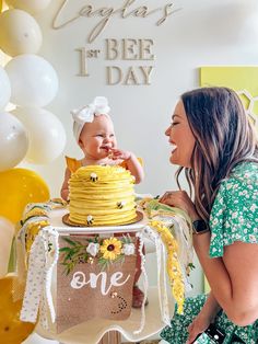 a woman holding a baby in front of a cake