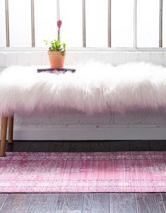 a bench with a pink rug and potted plant