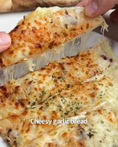 two pieces of cheesy garlic bread are being held by someone's hand