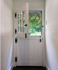 an empty hallway with a white door and black trim on the side walk leading to a window