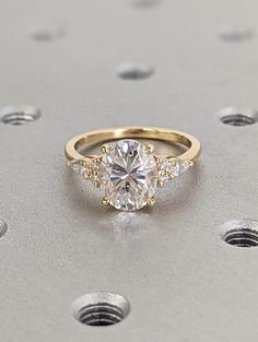 an engagement ring with three stones on top and two diamonds around the band, set in yellow gold