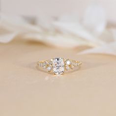 a diamond ring sitting on top of a white cloth covered tablecloth next to a flower