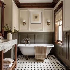 a white bath tub sitting under a window next to a sink and a wooden framed mirror