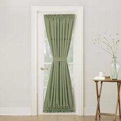 an open door with a green curtain in front of it and a small table next to it