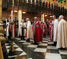 a group of men standing in front of a priest on a black and white checkered floor