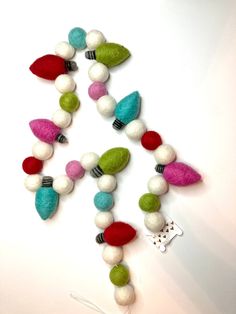 a necklace made out of felt beads and other colorful items on a white surface with a string attached to it