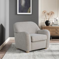 a living room with gray walls and a grey chair in front of a painting on the wall