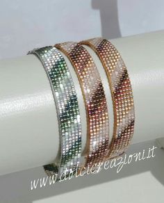 three bracelets are stacked on top of each other in gold, silver and green