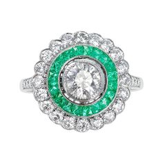 a green and white diamond ring with an oval center surrounded by smaller round brilliant cut diamonds