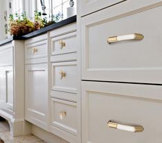 a kitchen with white cabinets and gold handles on the doors, drawers and cupboards