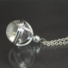 a silver necklace with a glass ball on it's end and a chain attached to it