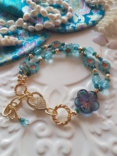 Delightful selection of blues in this Bohemian Beaded bracelet, close your eyes and let these pretty colours take you to that tropical place. This bracelet has been made with love and I have used assorted selection of super cute Czech glass beads, including these super cute Blue Hawaiian flowers and the most gorgeous Blue Frangipani focal bead. I have also used pretty gold faceted beads in the bracelet and included a extender chain on the bracelet. Bohemian Blue Czech Glass Bracelets, Blue Flower Bracelets For Beach, Blue Czech Glass Bracelet For Beach, Blue Czech Glass Bracelets For Beach, Blue Czech Glass Beach Bracelet, Blue Flower Beaded Bracelets For Beach, Blue Bohemian Bracelets With Spacer Beads, Bohemian Blue Bracelets With Spacer Beads, Turquoise Flower Bracelets With Colorful Beads