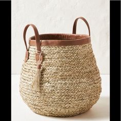 a large basket with handles and leather handles on the bottom is shown in front of a white wall