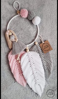 three different colored feathers with tassels hanging from the ends on a gray carpet