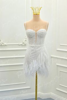 a mannequin wearing a white feather dress with a gold crown on it's head