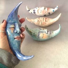 three ceramic masks are being held by someone's hand